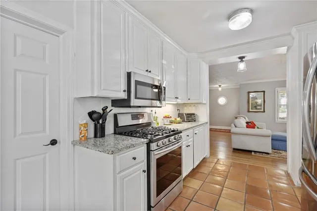 a kitchen with stainless steel appliances granite countertop a stove top oven a sink dishwasher and white cabinets with wooden floor