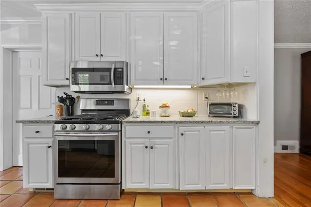 a kitchen with granite countertop white cabinets and stainless steel appliances