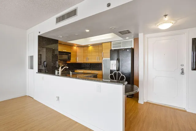 a view of a big room with wooden floor and a kitchen