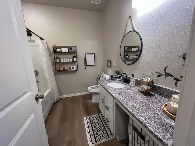 a bathroom with a granite countertop sink a toilet and a mirror