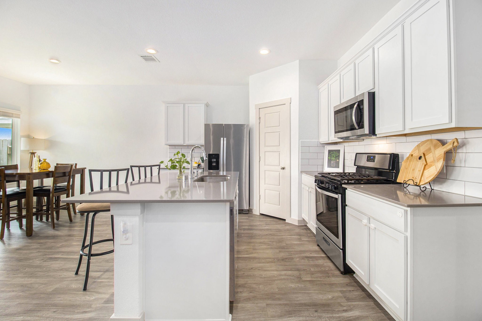 1823 William Scott Street Baytown, TX 77523 - Photo 12 of 27 a kitchen with stainless steel appliances a microwave a stove a sink dishwasher a refrigerator with white cabinets and wooden floor