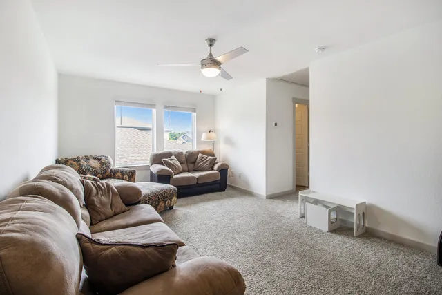 a living room with furniture and a ceiling fan