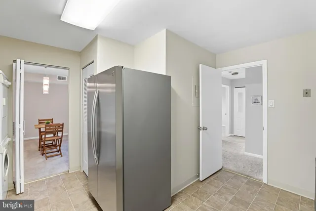 a view of a refrigerator in kitchen and an empty room