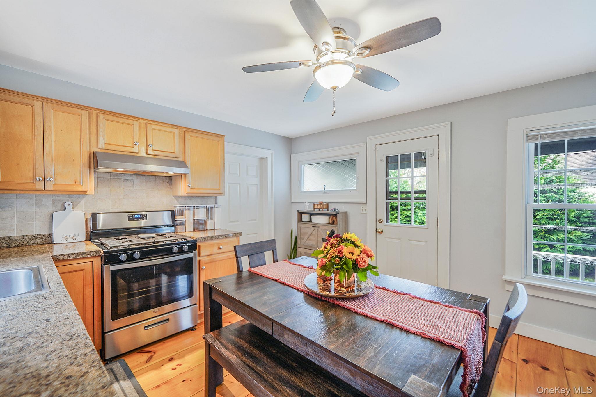 45 Maple Avenue Patchogue, NY 11772 - Photo 7 of 30 a kitchen with stainless steel appliances granite countertop a stove a dining table and chairs with wooden floor
