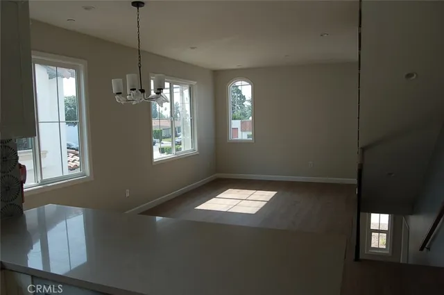 a view of an empty room with window and chandelier fan