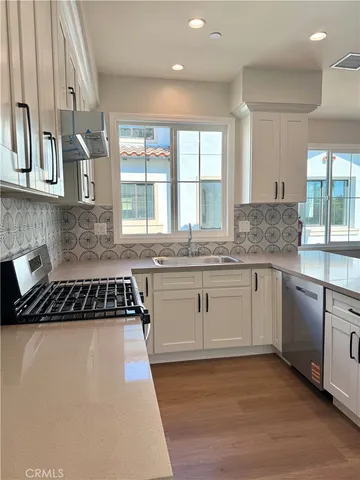 a kitchen with granite countertop a stove a sink and white cabinets