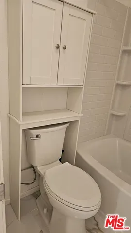 a white toilet sitting next to a bathtub