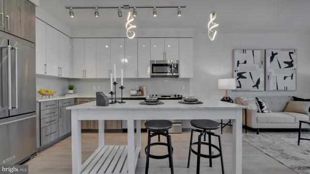 a kitchen with stainless steel appliances granite countertop a stove a refrigerator a sink a white table and chairs