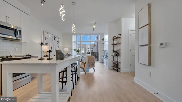 a kitchen with stainless steel appliances a dining table chairs refrigerator and cabinets