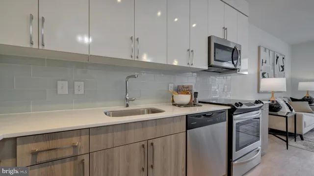 a kitchen with stainless steel appliances granite countertop a sink stove oven and white cabinets