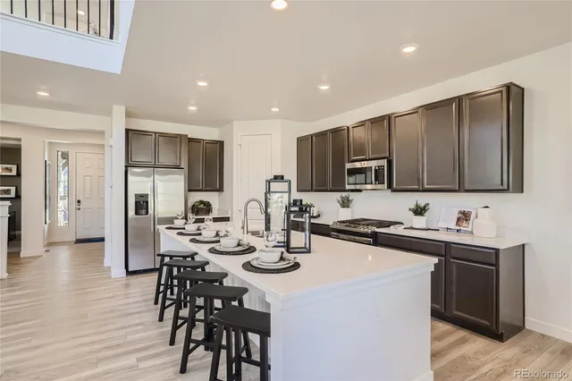 a kitchen with stainless steel appliances a table chairs refrigerator and microwave
