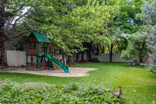 288 525 South Providence, UT 84332 - Photo 65 of 71 Expansive backyard featuring a lush lawn, mature trees providing ample shade, a sand play area with a built-in playset, and a private perimeter fence