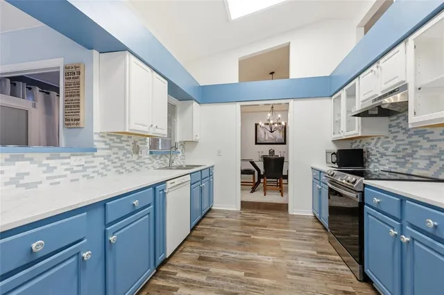 a large kitchen with granite countertop a stove top oven a sink dishwasher and wooden cabinets
