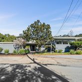 a front view of a house with a garden and tree