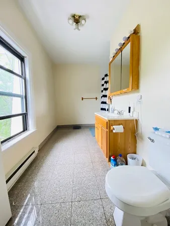 a bathroom with a sink mirror toilet and window