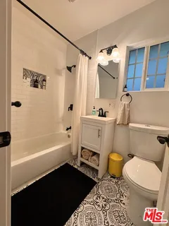 a bathroom with a sink a toilet a mirror a vanity and bathtub