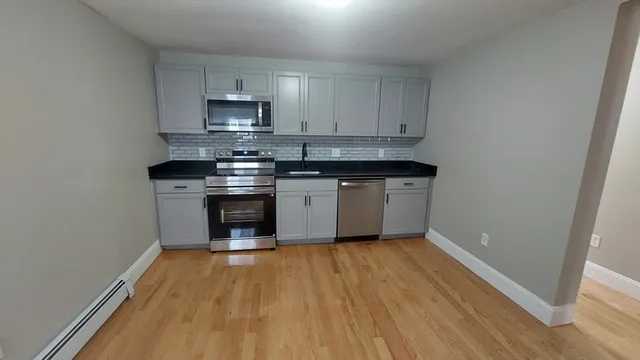 a kitchen with granite countertop wooden floors and stainless steel appliances