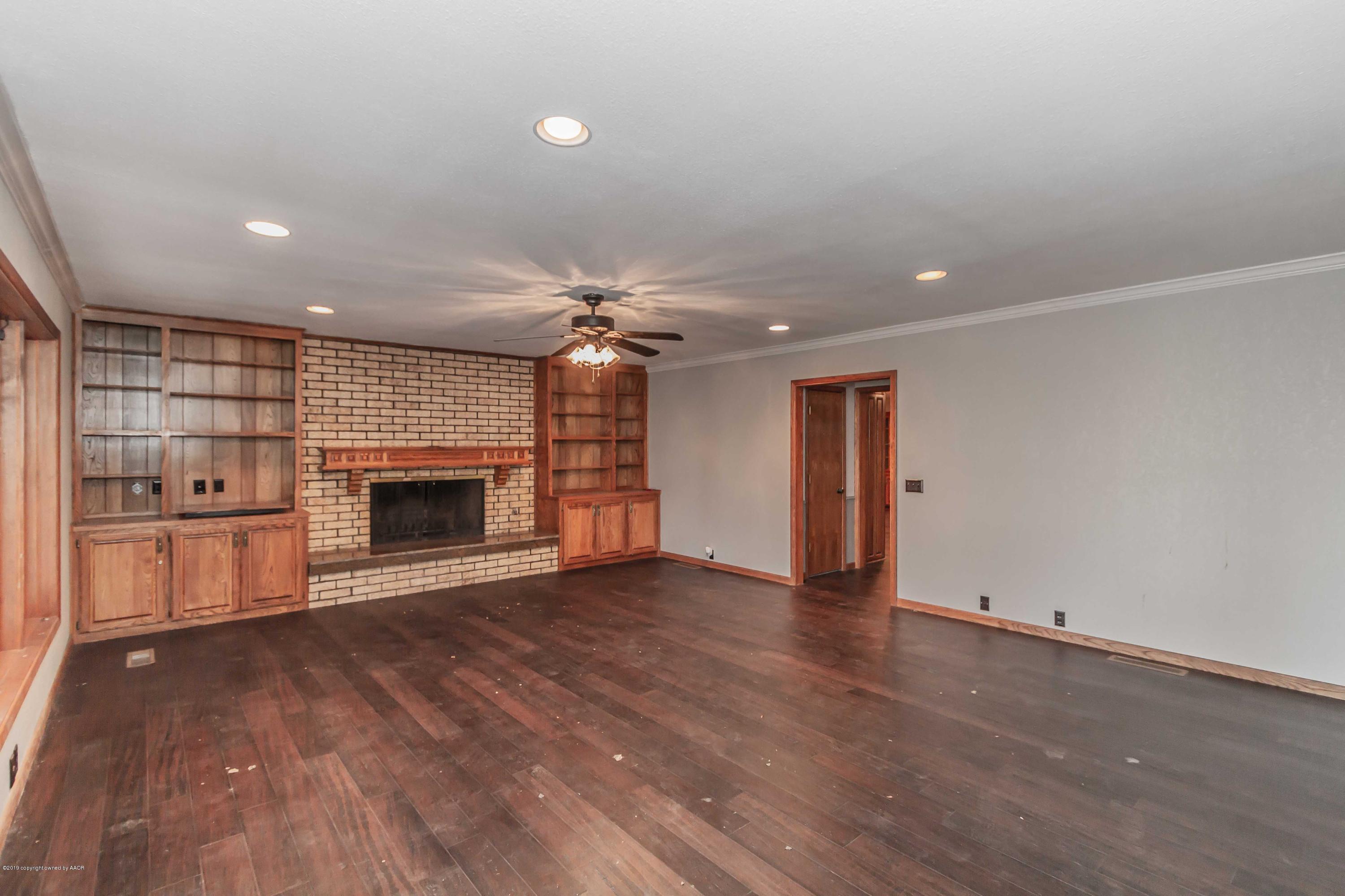 6801 Green Haven Road Amarillo, TX 79110 - Photo 14 of 65 an empty room with wooden floor fireplace and windows