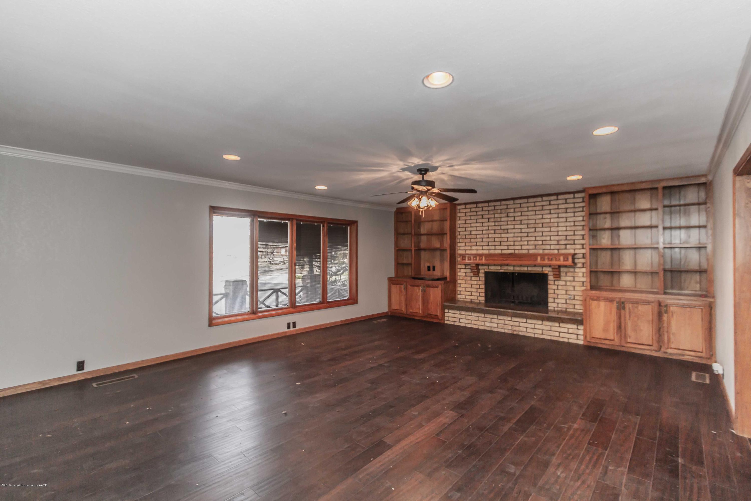6801 Green Haven Road Amarillo, TX 79110 - Photo 15 of 65 an empty room with wooden floor fireplace and windows