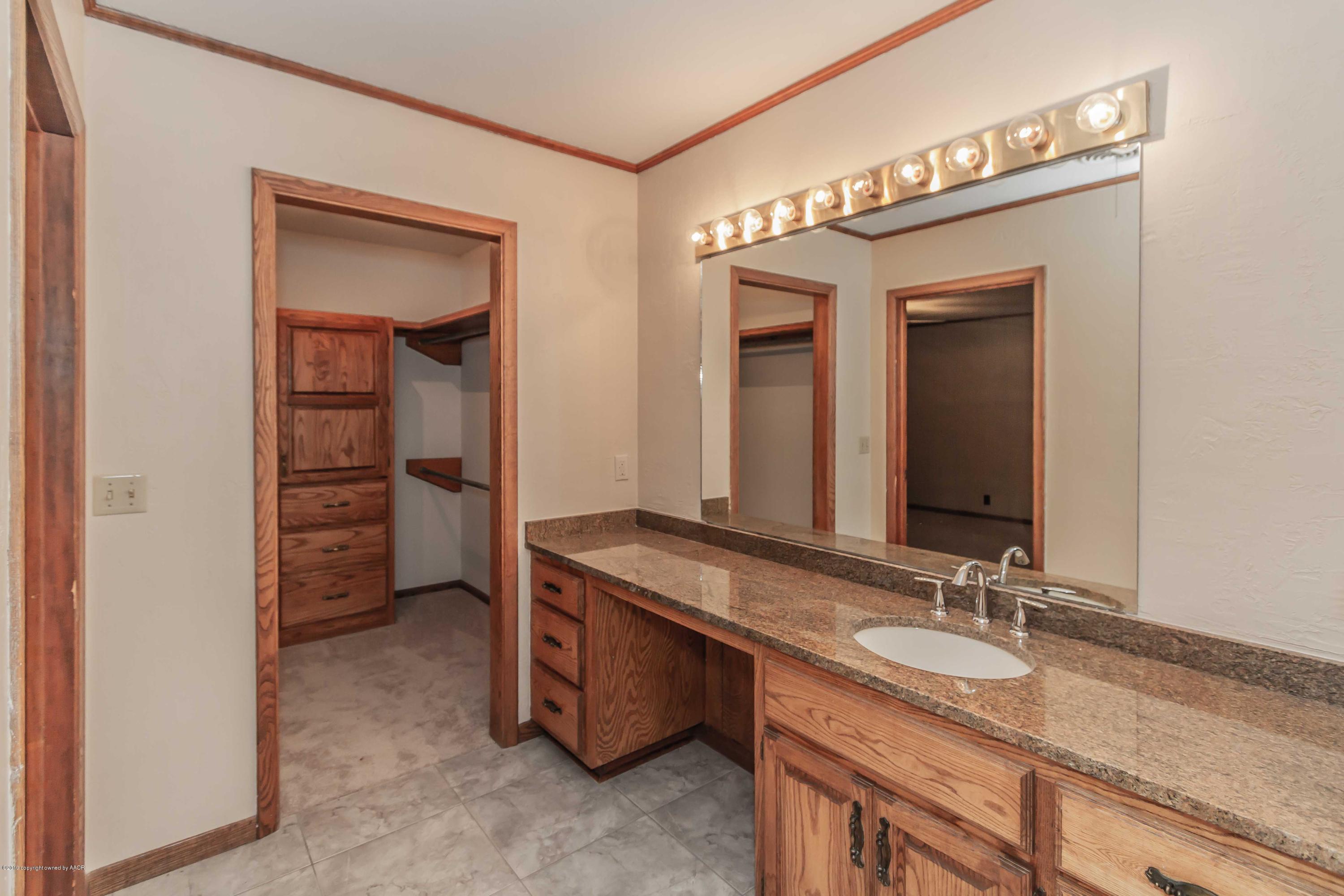6801 Green Haven Road Amarillo, TX 79110 - Photo 27 of 65 a bathroom with a granite countertop sink and a mirror