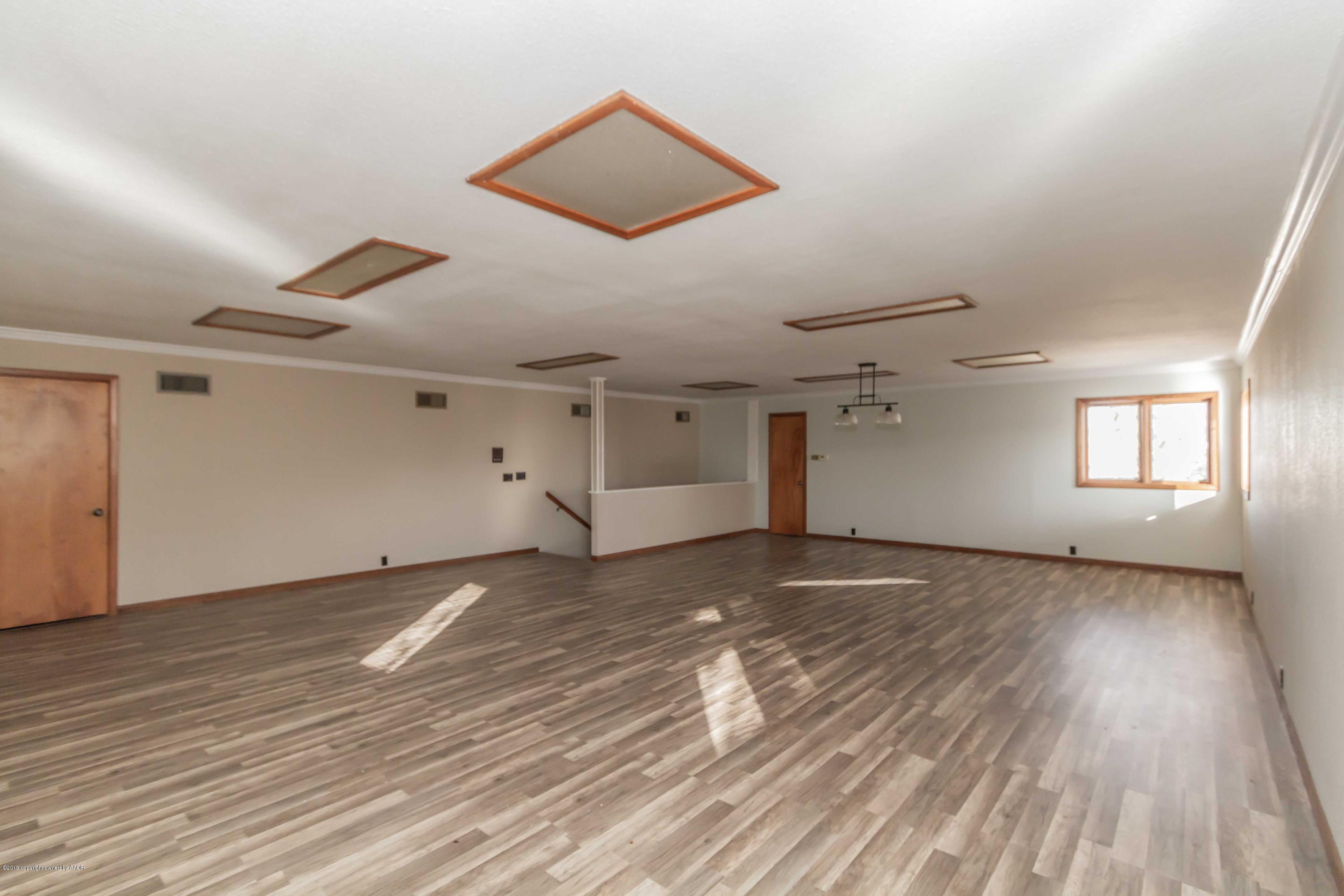 6801 Green Haven Road Amarillo, TX 79110 - Photo 50 of 65 an empty room with wooden floor a ceiling fan and windows