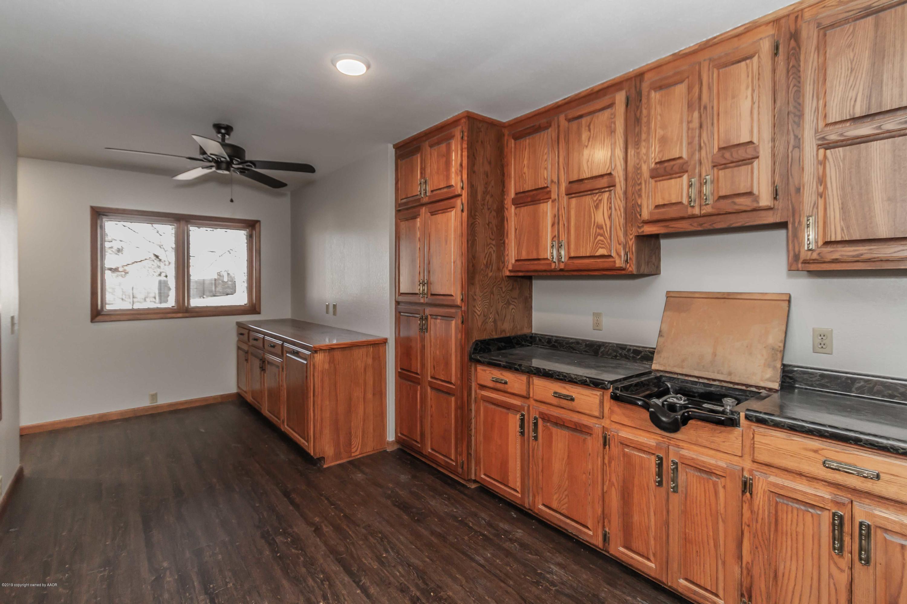 6801 Green Haven Road Amarillo, TX 79110 - Photo 56 of 65 a kitchen with granite countertop a stove cabinets and wooden floor
