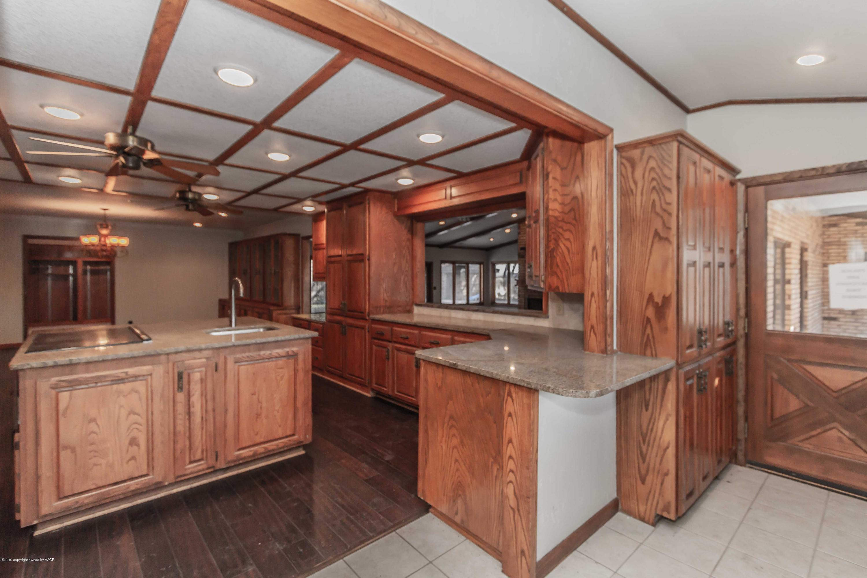 6801 Green Haven Road Amarillo, TX 79110 - Photo 8 of 65 a kitchen with stainless steel appliances granite countertop a sink and dishwasher with wooden cabinets