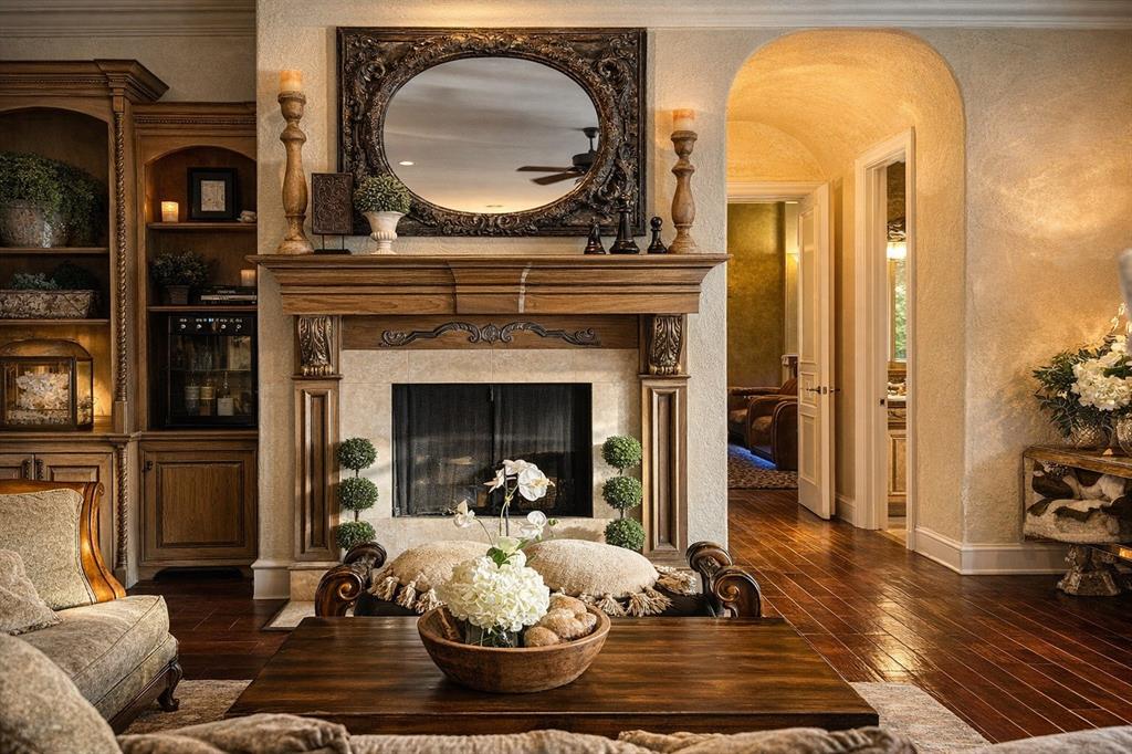 1919 Kings Pass Heath, TX 75032 - Photo 13 of 38 The living area features hardwood floors, a stone fireplace with an ornate wooden mantel, and built-in wooden cabinetry