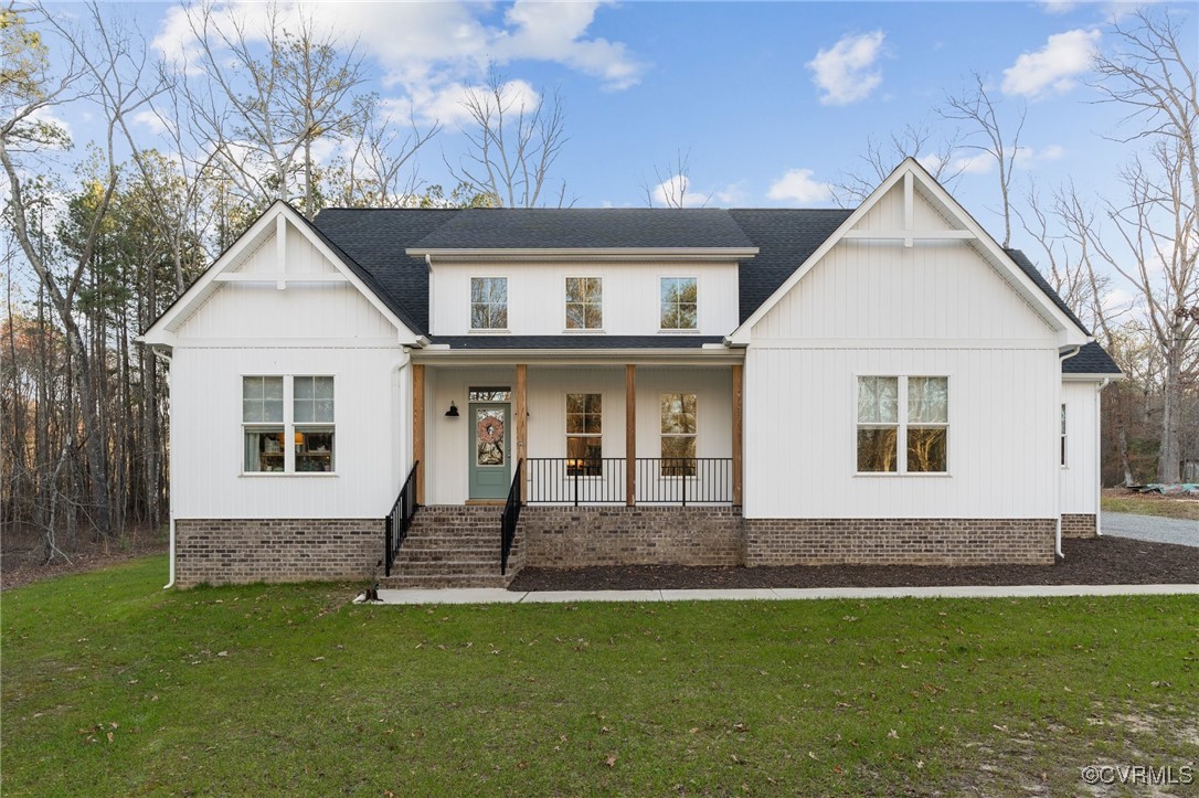 Modern farmhouse with a porch, a front lawn, and r