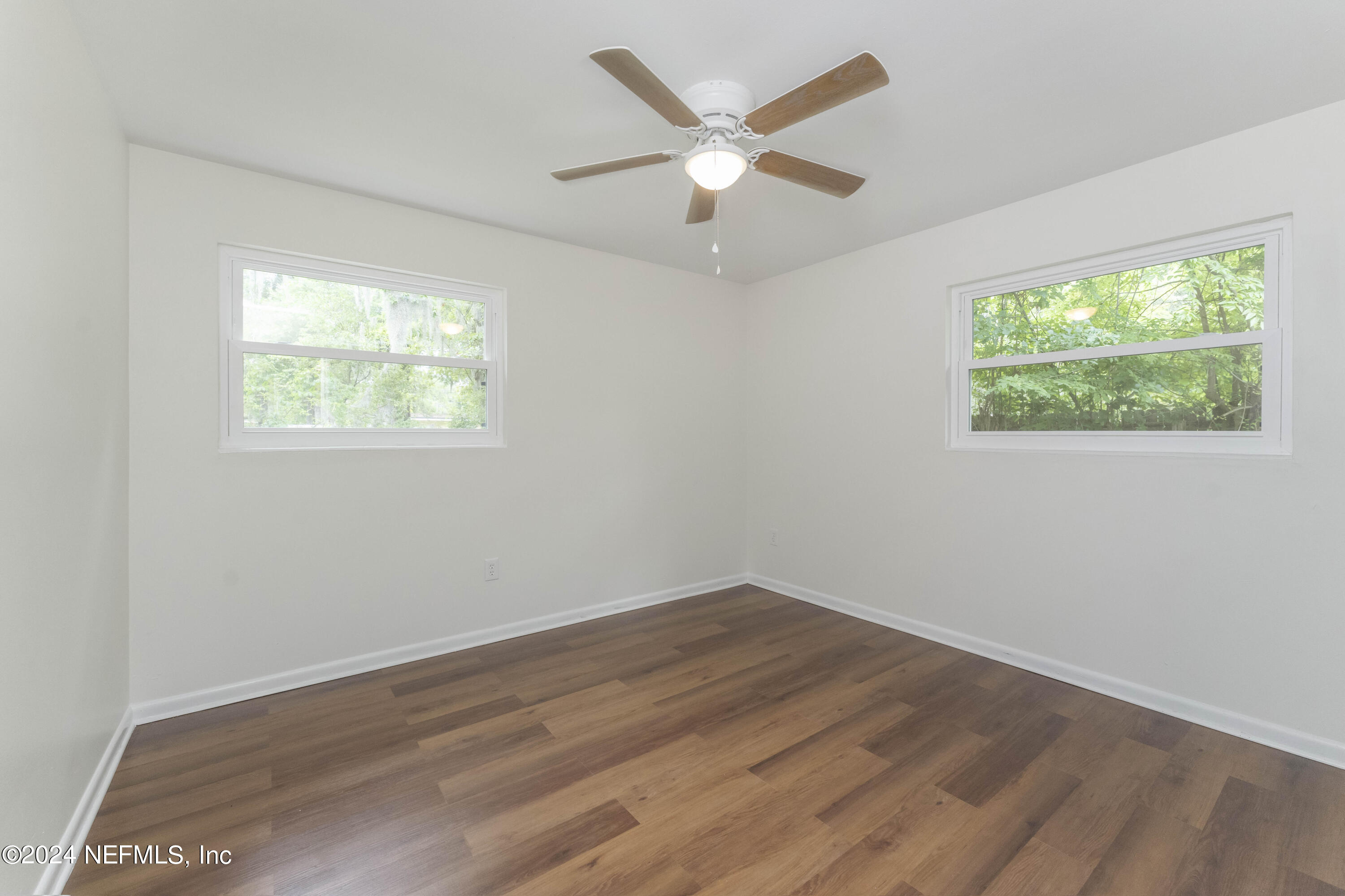 6937 Rollo Road Jacksonville, FL 32205 - Photo 15 of 26 a view of an empty room with wooden floor and a window