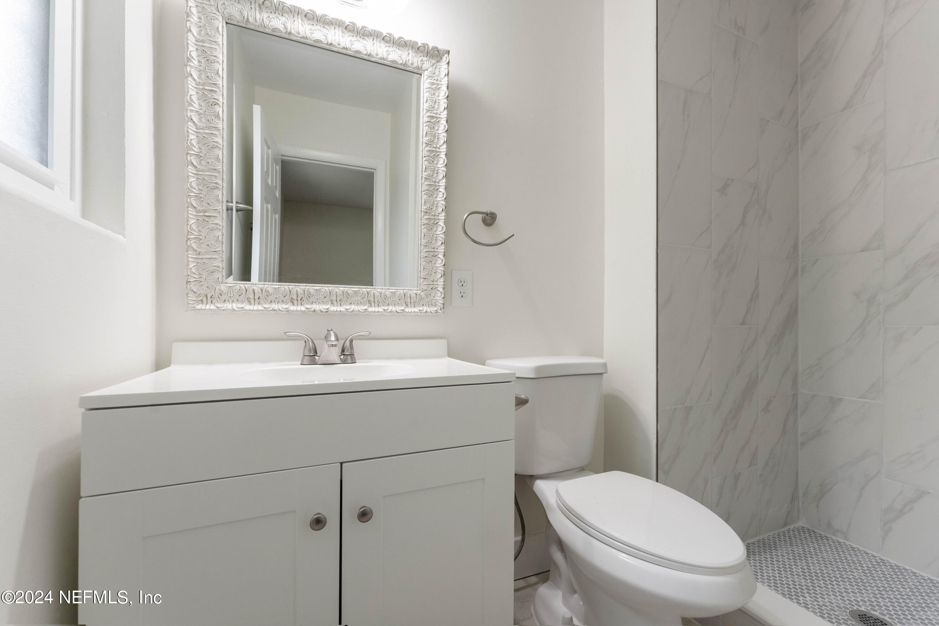 6937 Rollo Road Jacksonville, FL 32205 - Photo 17 of 26 a bathroom with a toilet sink vanity and mirror