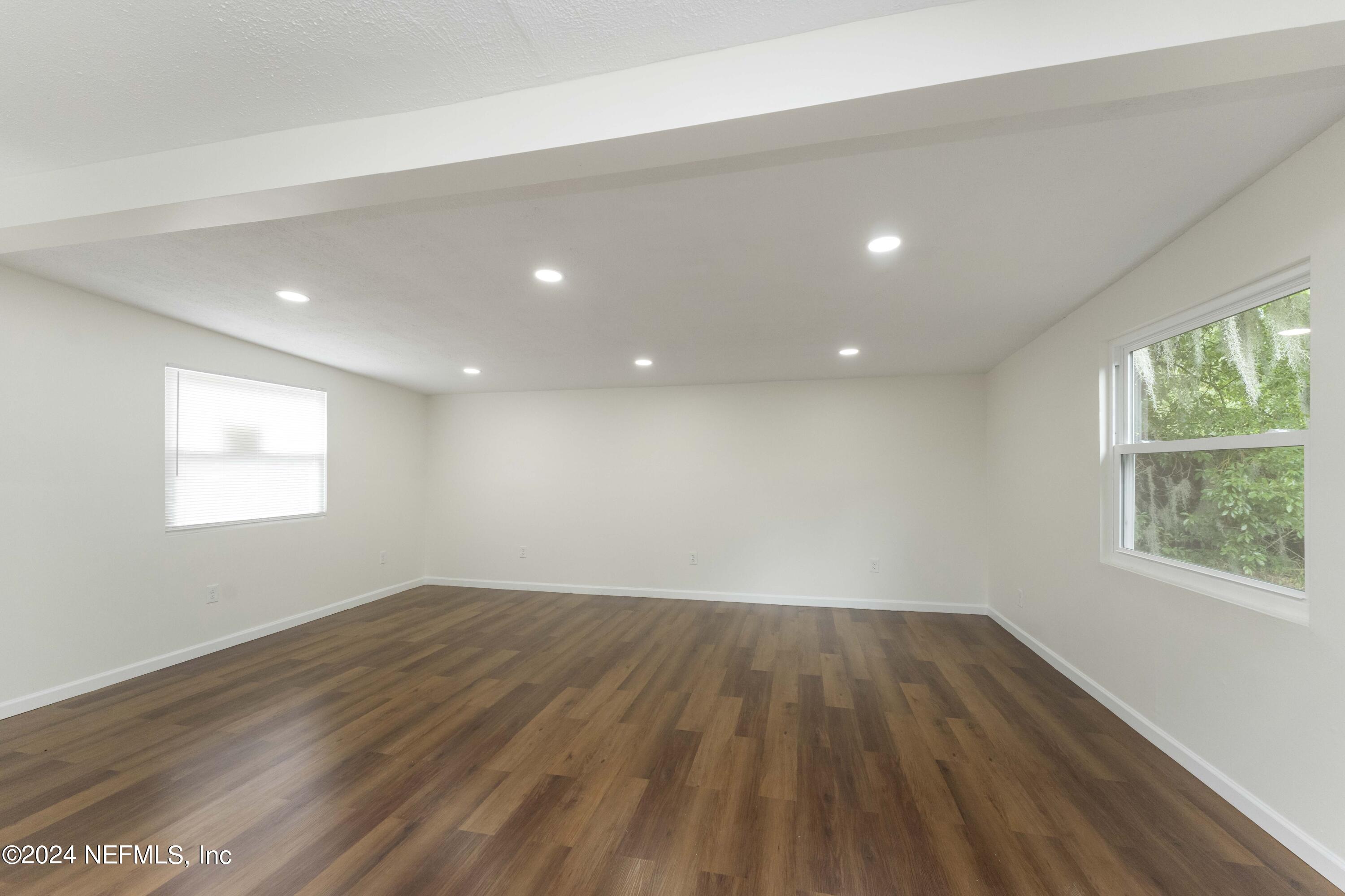 6937 Rollo Road Jacksonville, FL 32205 - Photo 4 of 26 an empty room with wooden floor and windows