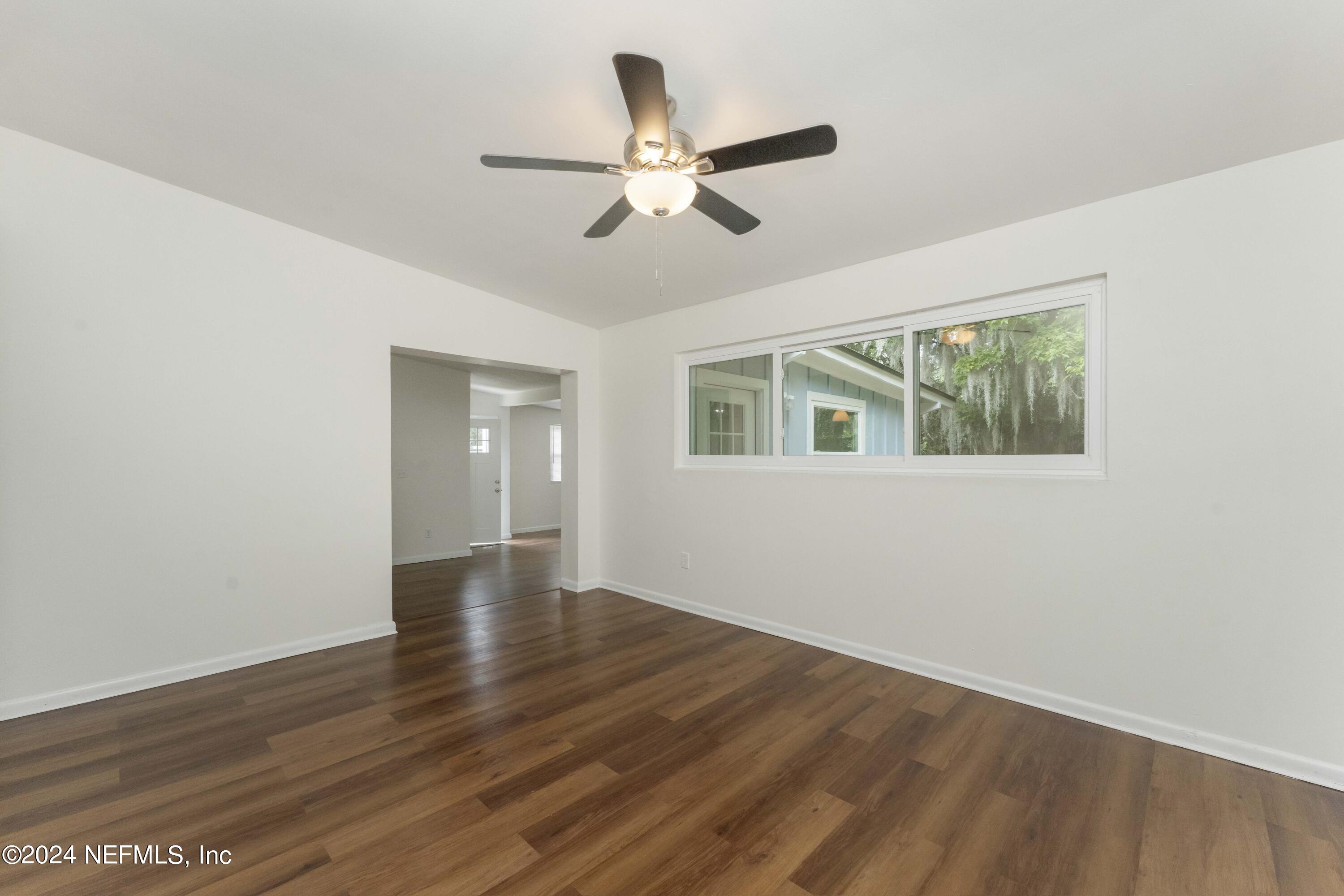 6937 Rollo Road Jacksonville, FL 32205 - Photo 6 of 26 a view of an empty room with wooden floor and a ceiling fan