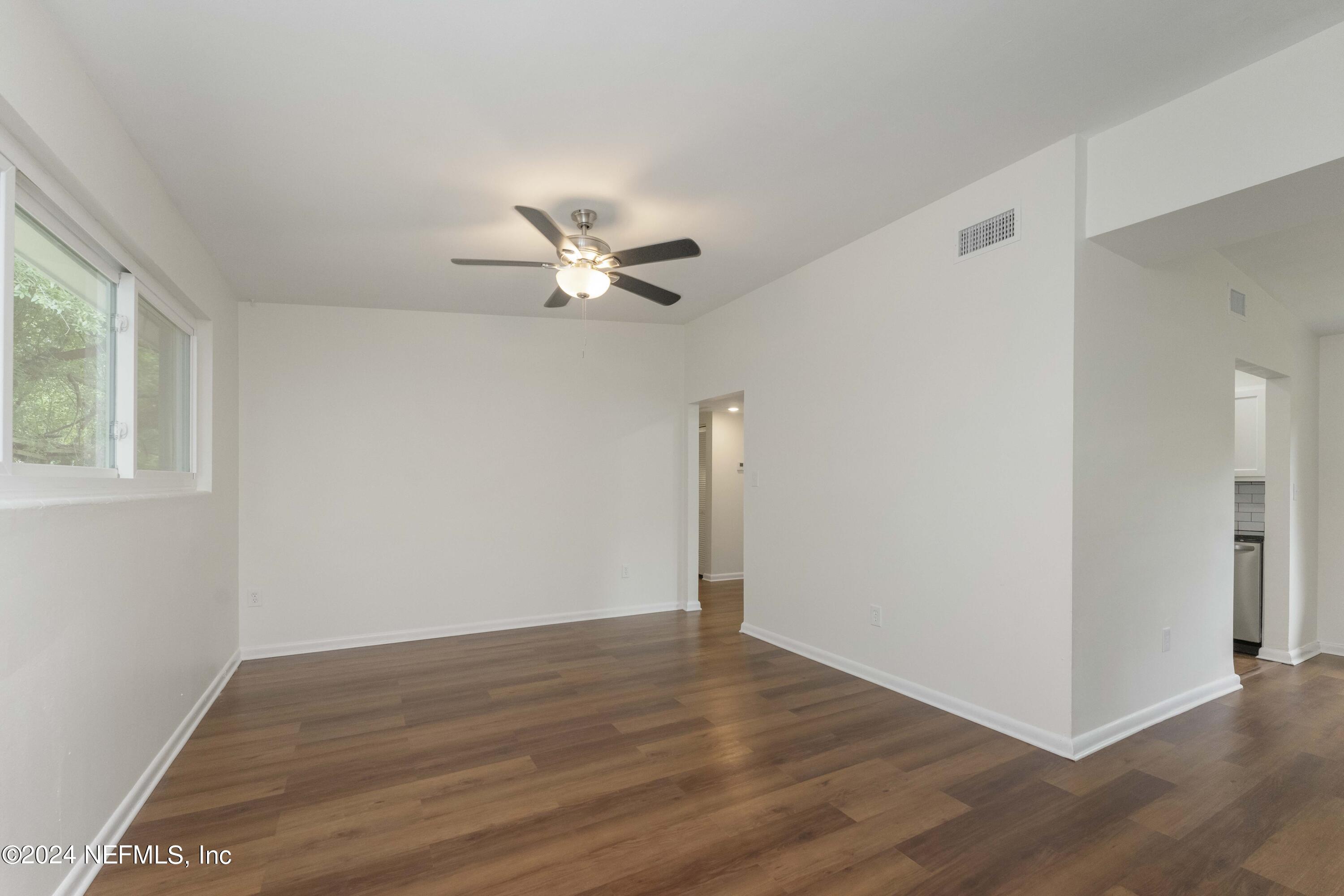 6937 Rollo Road Jacksonville, FL 32205 - Photo 7 of 26 a view of an empty room with wooden floor and a window