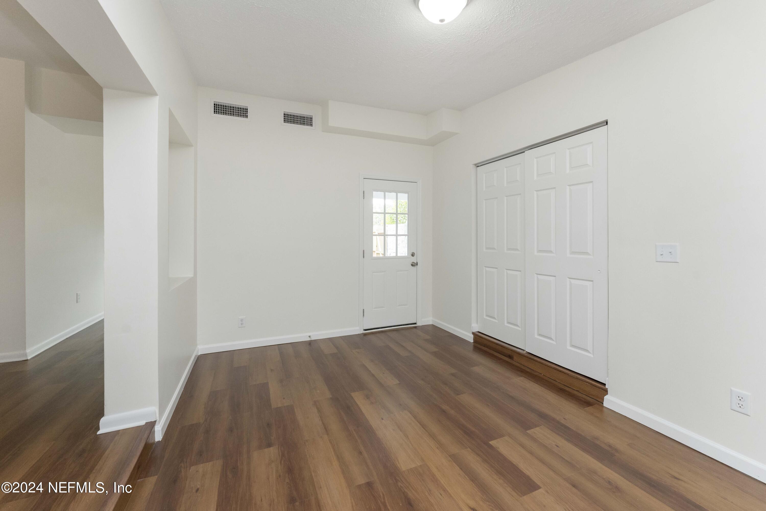 6937 Rollo Road Jacksonville, FL 32205 - Photo 8 of 26 an empty room with wooden floor and windows