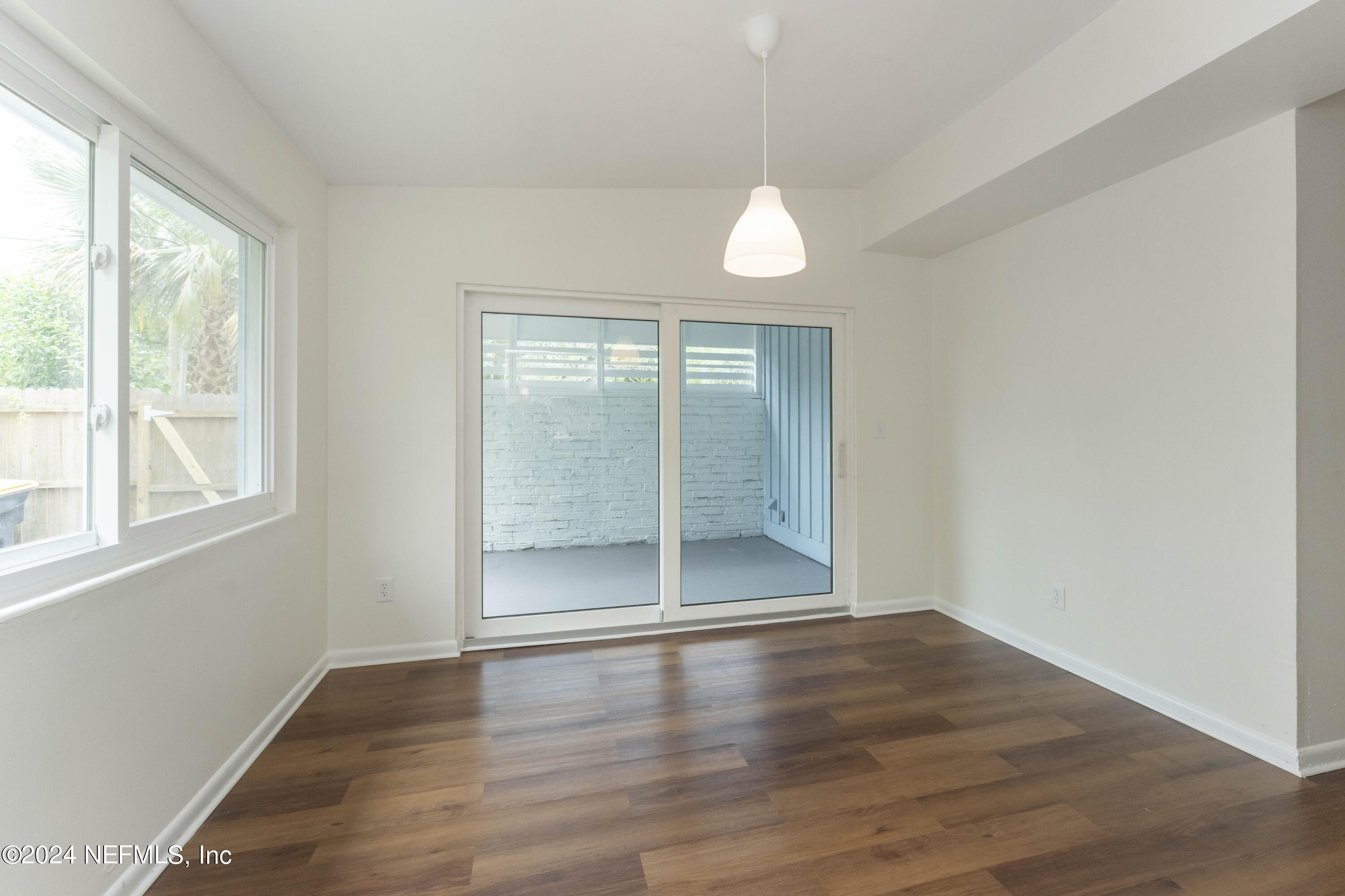 6937 Rollo Road Jacksonville, FL 32205 - Photo 10 of 26 an empty room with wooden floor and windows
