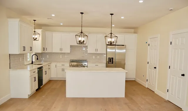 a large kitchen with stainless steel appliances granite countertop a sink a stove and a wooden floors