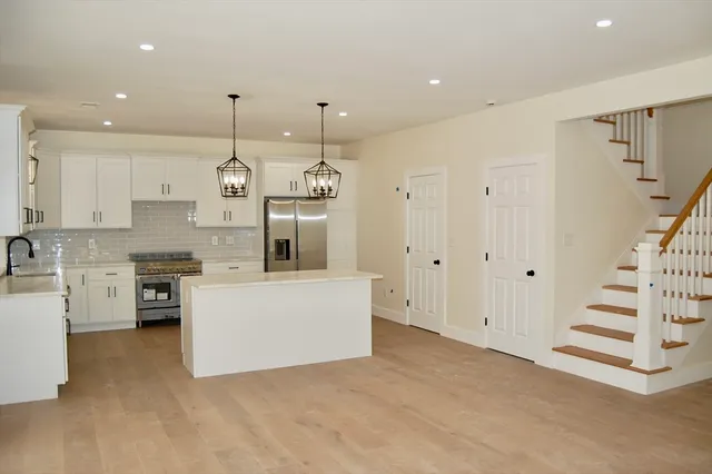 a large white kitchen with white cabinets and stainless steel appliances