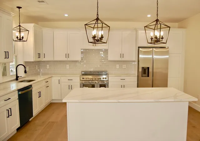 a kitchen with stainless steel appliances granite countertop a stove a sink and a refrigerator