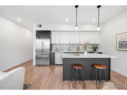 a kitchen with stainless steel appliances a dining table chairs and wooden floor
