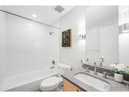 a bathroom with a granite countertop sink a toilet a mirror and bathtub
