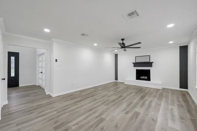 a view of a livingroom with a fireplace a ceiling fan and wooden floor