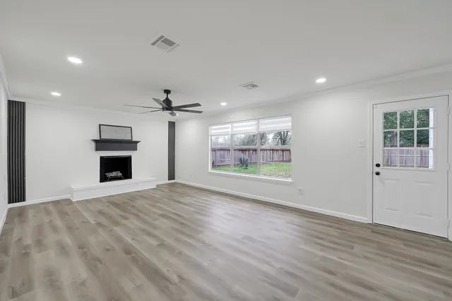 an empty room with wooden floor fireplace and windows