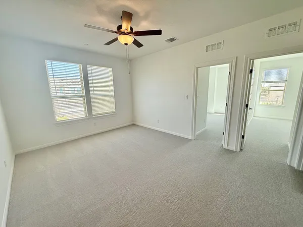 an empty room with windows and fan