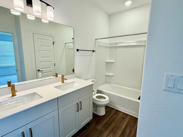 a bathroom with a sink a toilet a mirror a bathtub and shower