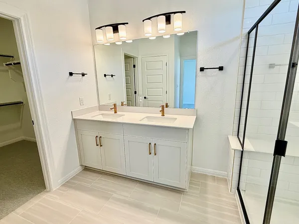 a spacious bathroom with a double vanity sink a mirror and a shower