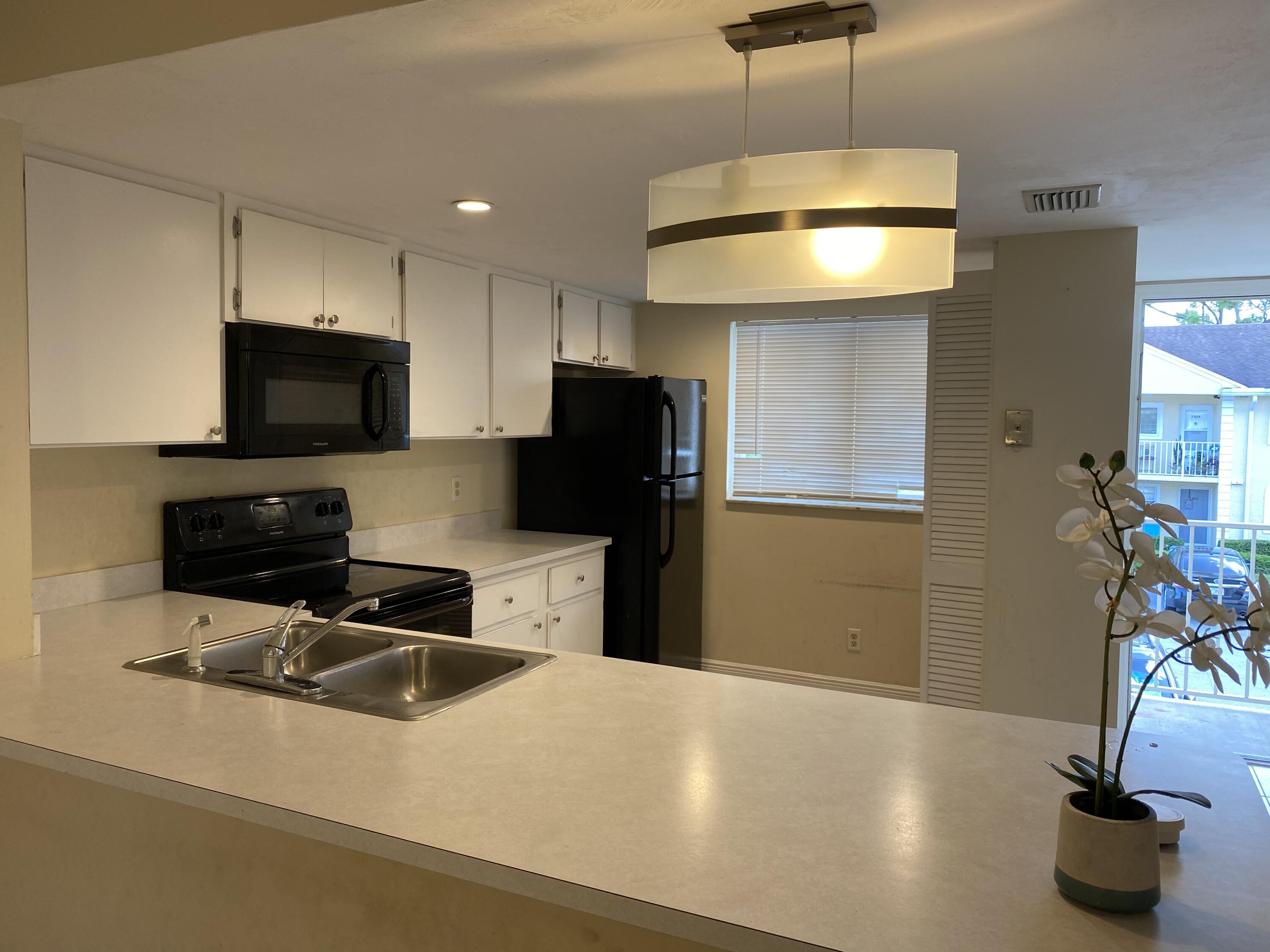 1707 Palm Beach Trace Drive, Unit 1707 Royal Palm Beach, FL 33411 - Photo 4 of 9 a kitchen with stainless steel appliances a refrigerator sink and microwave
