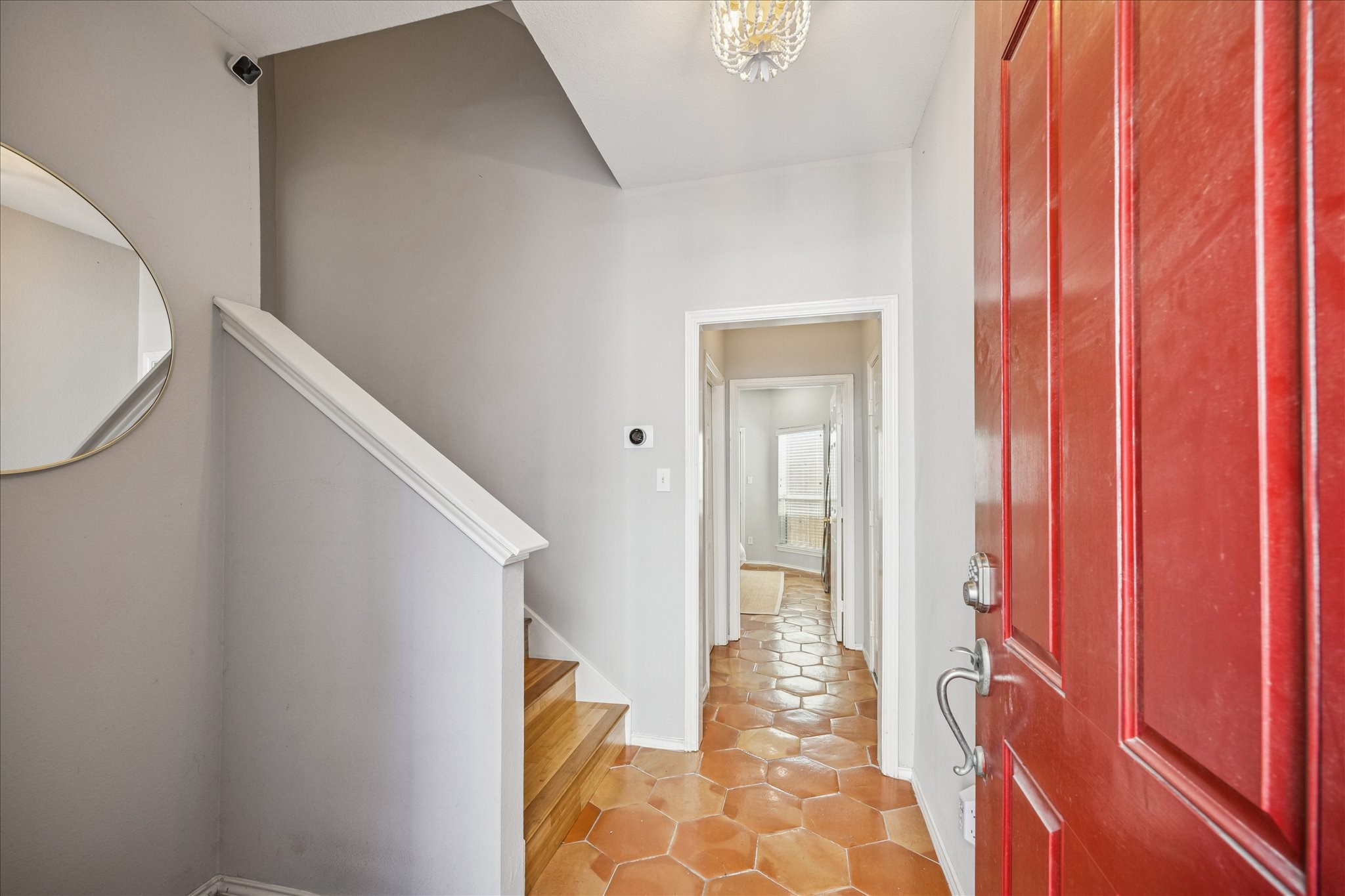 2607 Link Road Houston, TX 77009 - Photo 4 of 21 This welcoming entryway features a bold red door, terracotta tile flooring, and a staircase with wooden steps. The space is bright and airy, with neutral walls and a decorative mirror adding style. A hallway leads to additional rooms, enhancing the home's open feel.