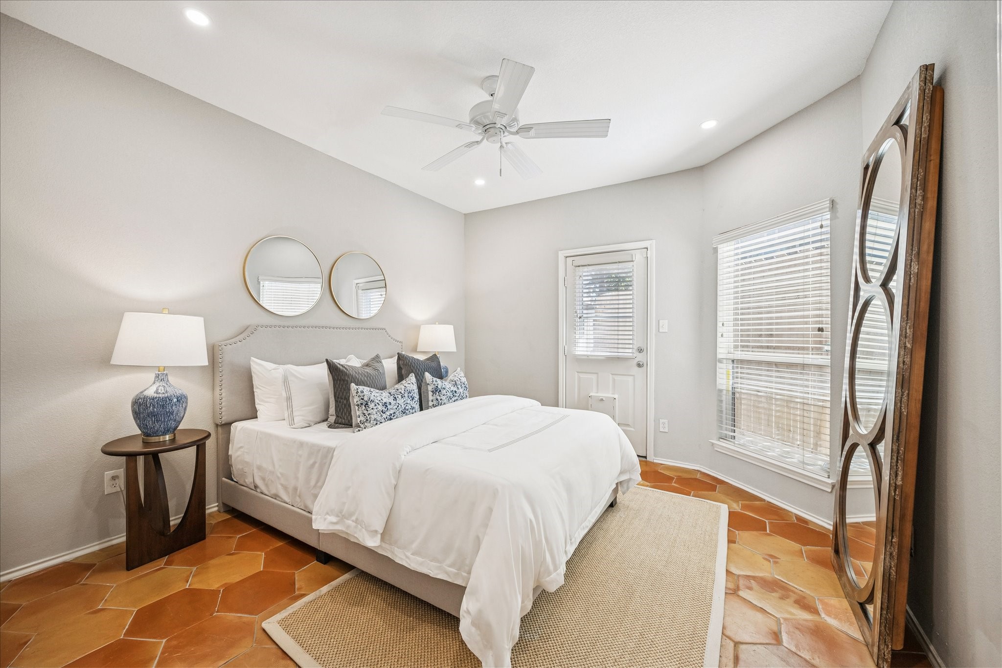 2607 Link Road Houston, TX 77009 - Photo 5 of 21 Inviting first floor Bedroom features warm terracotta tile flooring and a private door to the outside. The room is brightened by natural light from large windows to create a serene and comfortable atmosphere.