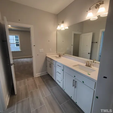 a spacious bathroom with a double vanity sink a mirror and a shower